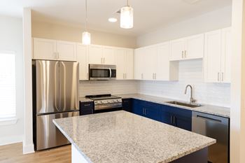 A kitchen with a granite countertop and stainless steel appliances at The Crest at Oakwood Apartments, Oakwood , GA